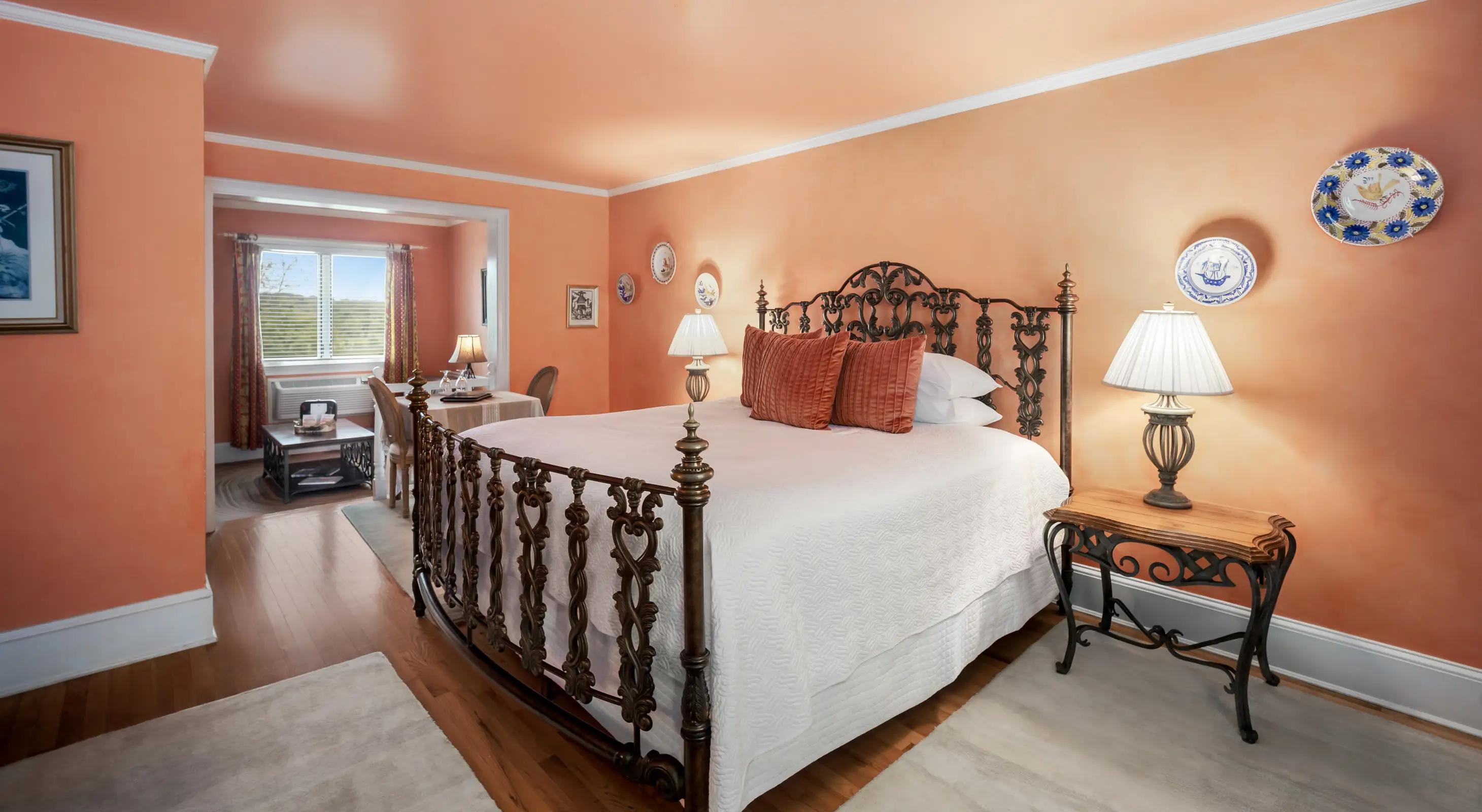 Spacious room with a coral walls, wrought iron bed, and a seating area near a window with scenic views. Shenandoah Valley