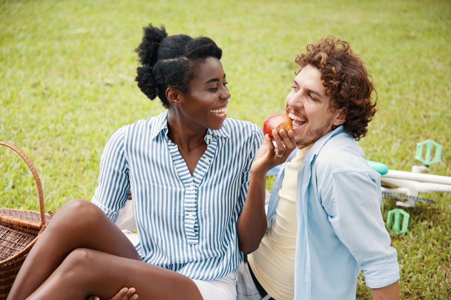 a man and woman eating an apple on a picnic