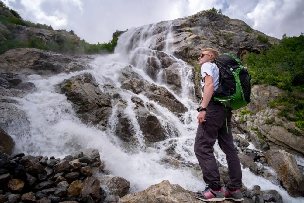 a man hiking near a waterfall